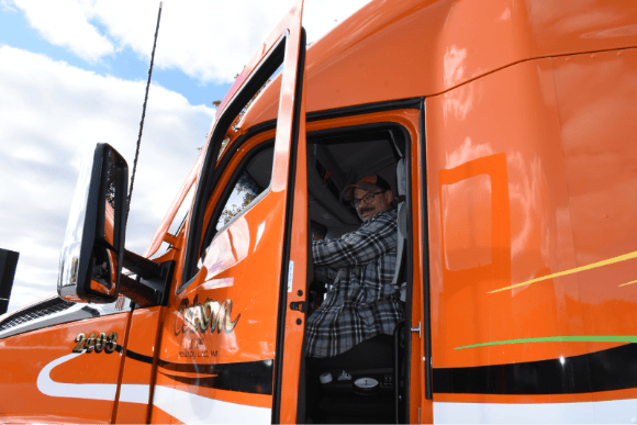 A happy Osborn driver smiling with his truck door open, sitting in the driver's seat